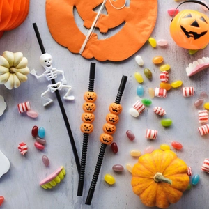 Detail of Halloween straws with 3D skull and orange pumpkin decors on textured background