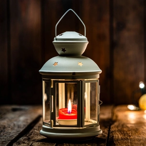 European vintage white metal star lantern with red candle on a wooden table