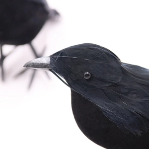 Detailed close-up of realistic black faux feathers and grey beak on Halloween crow prop