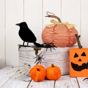 Halloween decor set with black crow, orange pumpkins, and scary skull hand on wood floor