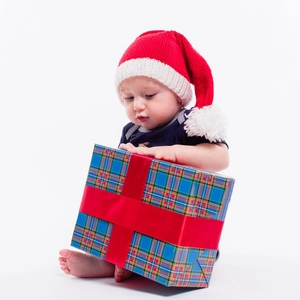 Infant red Christmas knit hat with pom-pom and large blue plaid gift box with red ribbon