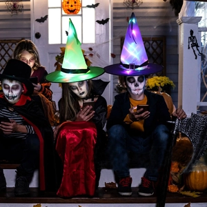 Kids wearing glowing LED wizard hats in green and purple during Halloween night