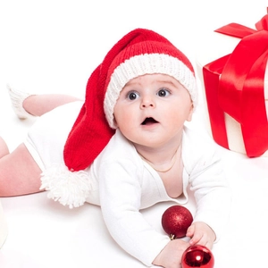 Infant Christmas knit set with long tail pompom hat and white romper on festive background
