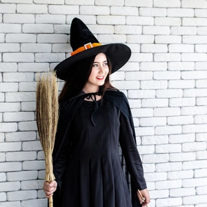 Close-up of black Halloween witch costume featuring a pointed hat with orange buckle and cape