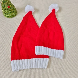 Flat lay of red and white knitted Christmas parent-child hats with soft pom-pom detail
