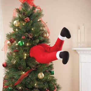 Funny plush Santa legs sticking out of a decorated Christmas tree with red pants and black boots