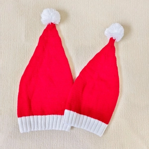 Matching parent and child red knitted Christmas hats with white pom-poms and ribbed cuffs