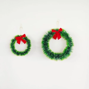Close-up of two green Christmas tinsel wreaths with red bows and golden hanging cords