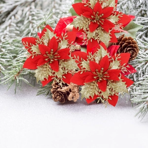 Close-up of red artificial poinsettia with gold glitter on snowy pine branches