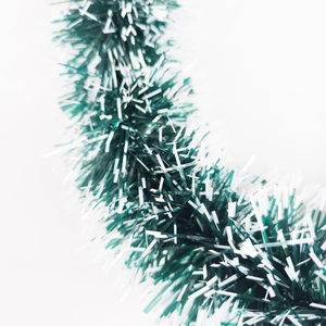 Macro detail of dense green Christmas tinsel garland with white frosty tips for decor