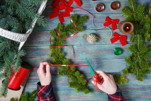 Flat lay of Christmas DIY wreath kit with fir branches, red bows, and crafting tools