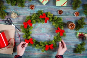 Flat lay of Christmas wreath with red satin bows on a vintage wooden table setting
