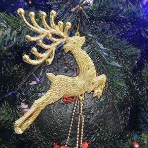 Golden Christmas reindeer ornament with beaded texture hanging on a green festive tree