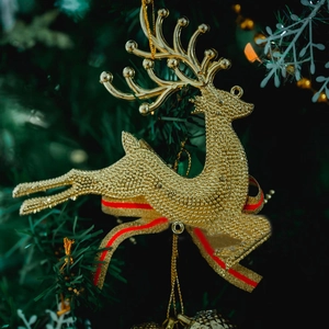 Close-up of golden reindeer Christmas ornament with red ribbon on a festive tree branch
