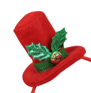 Nahaufnahme eines roten Mini-Weihnachtshutes mit grünen Stechpalmenblättern und Glocke