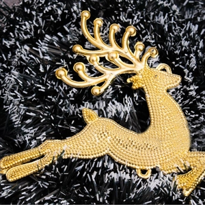 Golden Christmas reindeer ornament with textured finish on a festive garland background