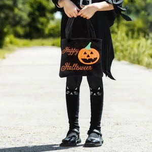 Kid carrying a plush black Halloween candy bag with pumpkin design and orange text