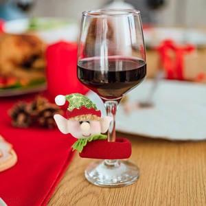 Christmas elf wine glass charm with green sequins and felt fabric on holiday dinner table