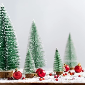 Miniature flocked Christmas trees with wooden bases and red ornaments on snow tabletop