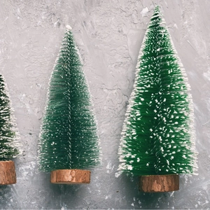 Mini artificial Christmas trees with snow-dusted pine needles and wooden base
