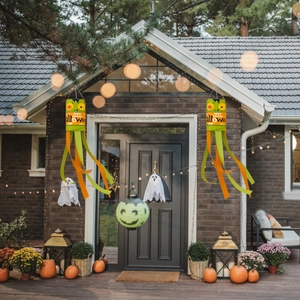 Detail of two Frankenstein Halloween windsocks hanging on a porch with pumpkins