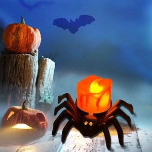 Halloween spider LED candle with orange flame effect on a rustic pumpkin background