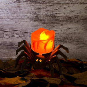 Detail of Halloween spider LED candle light with melting wax effect on wooden surface