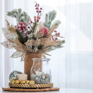 Bouquet de Noël avec feuilles dorées et baies rouges en vase sur plateau doré au bord