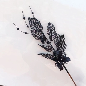 Détail d'une branche de Noël à paillettes noires avec feuilles évidées et baies