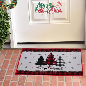 Detail der Weihnachtsmatte mit Karo-Bäumen und Merry Christmas Text auf Ziegelboden