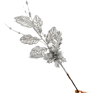 Détail de branche artificielle argentée avec paillettes, feuilles ajourées et petites baies