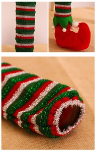 Detailed view of striped Christmas elf leg covers for chairs with red boots and pom-poms