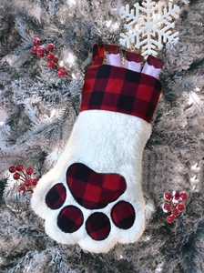 Detail of plush paw-shaped Christmas stocking with red buffalo plaid trim and bone treat
