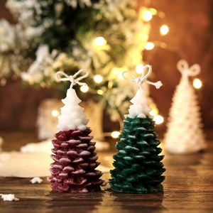Detalle de velas con forma de árbol de Navidad granate y verde con efecto de nieve