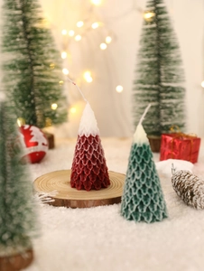 Detailed view of tree-shaped Christmas candles with snow effect on a wooden base