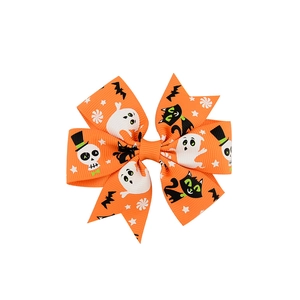 Détail d'un nœud pour cheveux orange Halloween avec motifs de fantômes et squelettes