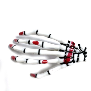 Detail of white skeleton hand hair clip with red nails and realistic bone joints