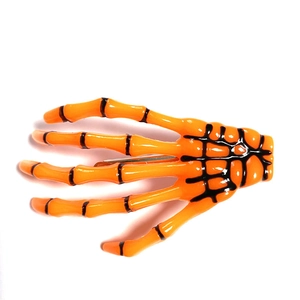 Macro view of bright orange skeleton hand hair clip with black detail and metal clip back