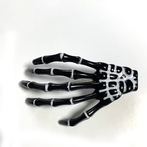 Detailed view of the metal spring clip on the back of the skeleton hand hair accessory