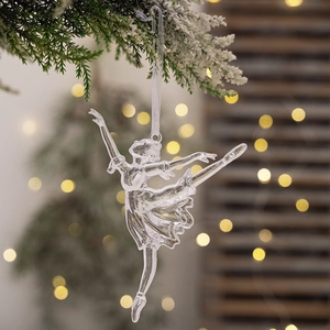 Close-up of clear acrylic ballet girl ornament hanging on a frosty Christmas tree branch