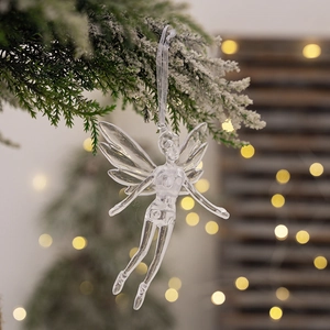 Clear acrylic angel ornament with wings on snowy Christmas tree branch with warm lights