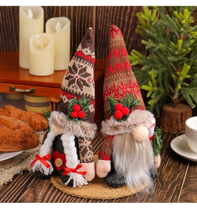 Macro shot of plush Christmas gnomes with knit hats and candy cane on a festive table