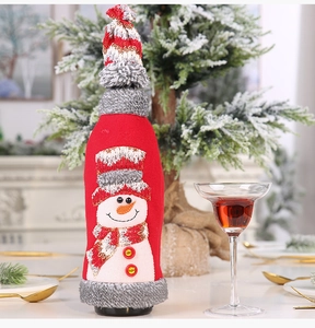 Close-up of red wine bottle cover with snowman embroidery and festive knitted hat