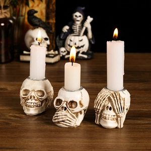 Three skeleton skull candle holders for Halloween with resin finish on a wooden table