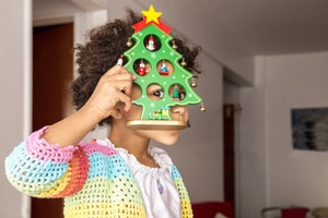 Detail of wooden Christmas tree decor with miniature figures and a girl holding it