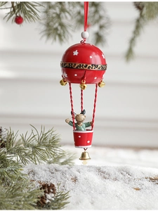 Détail d'une décoration de Noël en forme de montgolfière rouge suspendue à un sapin enneigé