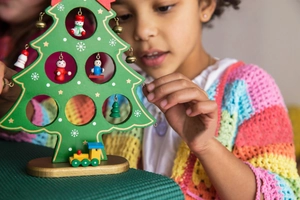 Detail of wooden Christmas tree with mini snowman pendants and a small toy train base