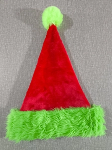 Détail du bonnet de Noël en peluche rouge avec bordure et pompon en fausse fourrure verte