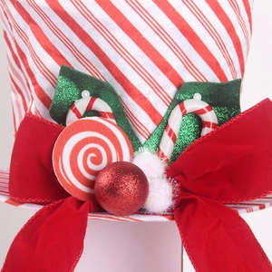 Detail of Christmas tree topper with red striped fabric, velvet bow, and glitter ornaments