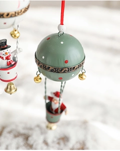 Gros plan sur l'ornement montgolfière de Noël verte avec Père Noël et grelots dorés
